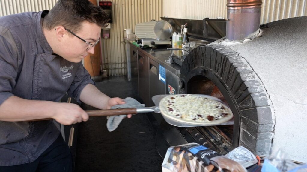 chef inserting pizza into pizza oven